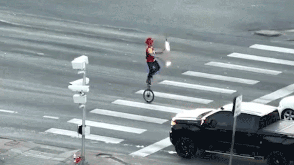 Image for the article: Fire-juggling unicyclist caught on camera blocking traffic in major roadway as police intervene